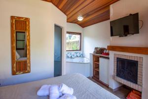 a bedroom with a bed and a fireplace at Pousada Flores da Serra in Monte Verde