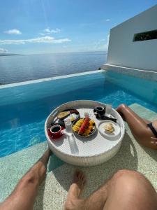 a man sitting on the edge of a pool with a tray of food at Epic Suites Bohol ADULTS ONLY in Dauis