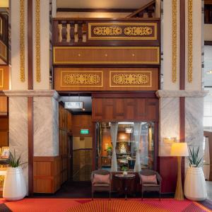 a lobby with a table and chairs in a building at Alexander Hotel in Bangkok