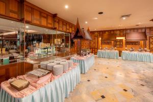 a restaurant with several tables with white plates on them at Alexander Hotel in Bangkok