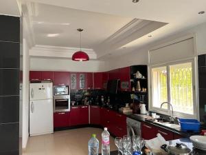 a kitchen with red cabinets and a white refrigerator at Botola Home 2 in Casablanca