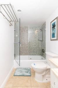 a white bathroom with a toilet and a shower at Modern Oceanview Condo - Steps to the Beach! in Miami Beach