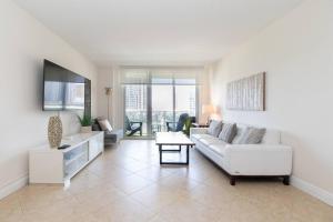 a living room with a white couch and a table at Modern Oceanview Condo - Steps to the Beach! in Miami Beach