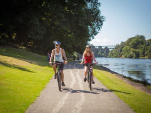 two people riding bikes down a path next to a lake at Quest on London in Hamilton