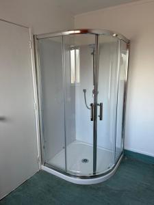 a glass shower with a glass door in a room at MALFROY Motor Lodge Rotorua in Rotorua