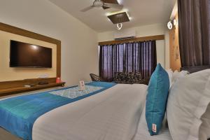um quarto de hotel com uma cama grande e uma televisão em Super OYO Hotel Siddharth Inn em Gandhinagar