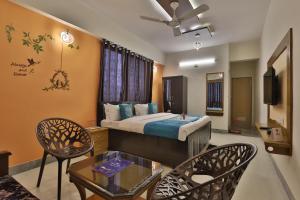 a hotel room with a bed and a table and chairs at Hotel Siddharth Inn in Gandhinagar