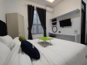 Cette chambre comprend un lit blanc avec une table verte. dans l'établissement Urbanview Badran Residence Syariah Manahan, à Solo