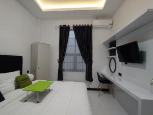 Habitación blanca con cama y mesa verde en Urbanview Badran Residence Syariah Manahan, en Solo