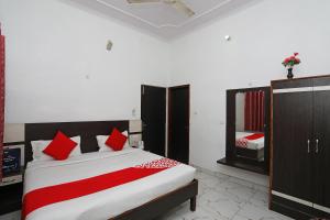 a bedroom with a bed with red pillows and a mirror at Hotel O Haveli Inn in Varanasi
