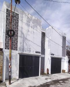 un bâtiment blanc avec deux portes latérales dans l'établissement Rumah Bahagia 36, à Bonorejo