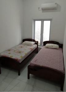 two beds sitting in a room with a window at Rumah Bahagia 36 in Bonorejo