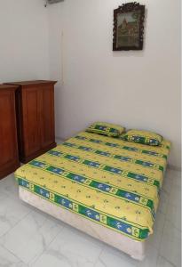 a bed with a yellow comforter in a bedroom at Rumah Bahagia 36 in Bonorejo