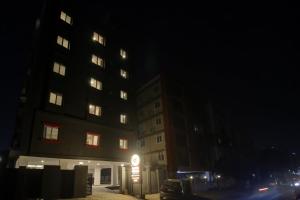 Super Townhouse 733 Whiteridge Gachibowli Near AIG Hospital في حيدر أباد: مبنى طويل في الليل مع وجود علامة أمامه