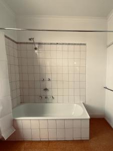 a bath tub in a bathroom with white tiles at The Daylesford Hotel in Daylesford