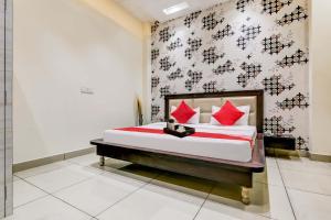 ein Schlafzimmer mit einem Bett mit roten Kissen in der Unterkunft Super OYO Flagship Hotel Sky Land in Ludhiana