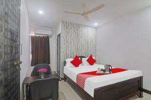 Un dormitorio con una cama con almohadas rojas y una silla en Super OYO Alwal Residency, en Hyderabad