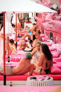 een groep mensen die op roze bedden zitten bij SocialTel Koh Samui in Chaweng Beach