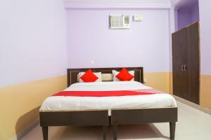 une chambre avec un lit avec des oreillers rouges dans l'établissement Hotel O Sunrise Inn, à Indirapuram