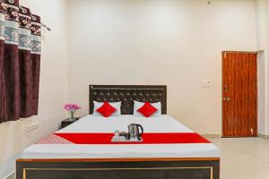 um quarto com uma cama com um cobertor vermelho e branco em OYO City Guest House em Varanasi