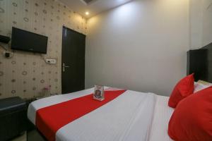 Cette chambre comprend un lit avec une couverture rouge et blanche. dans l'établissement OYO Hotel West Delhi Inn Near Tdi Mall, à New Delhi