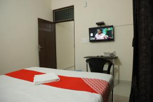 Zimmer mit einem Bett und einem TV an der Wand in der Unterkunft Hotel O Hmi International in Meerut