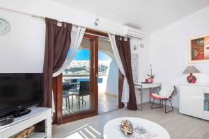 een woonkamer met een televisie en een tafel met stoelen bij Apartments in Baska - Insel Krk 42194 in Baška