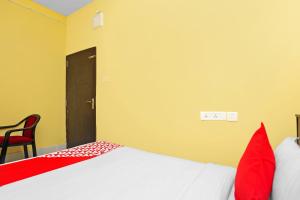 a bedroom with a bed and a red chair at OYO Seven Inn in Bhubaneshwar