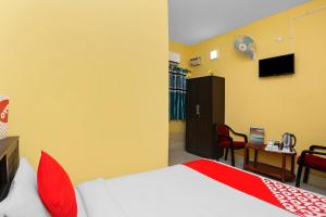um quarto com uma cama com almofadas vermelhas e uma secretária em OYO Seven Inn em Bhubaneshwar