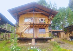 Cozy cabin Casa Enya في Sibundoy: منزل خشبي كبير مع شرفة كبيرة
