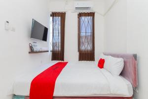 a bedroom with a white bed with a red blanket on it at RedDoorz near Pasar Lama Serang in Serang