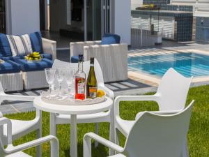 a white table with two bottles of wine and glasses at Protaras Seafront Villa Sirina Pearl in Protaras