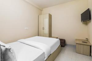 1 dormitorio con 1 cama blanca y TV en Super OYO Hotel Rameshwar, en Ranchi