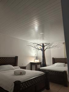 1 dormitorio con 2 camas y un árbol en la pared en Hotel Pacande B&B en Alajuela