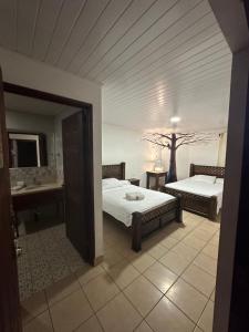 a bedroom with two beds and a bathroom with a sink at Hotel Pacande B&B in Alajuela