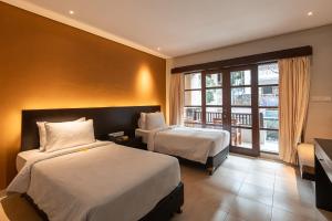a hotel room with two beds and a window at Fourteen Roses Beach Hotel in Legian