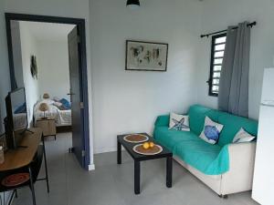 a living room with a green couch and a table at Vacances entre mer et colline in Oyster Pond