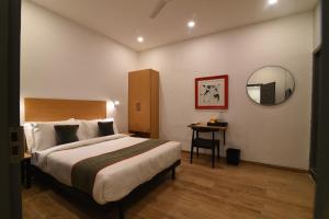 een slaapkamer met een bed, een spiegel en een tafel bij Townhouse Royapettah Near U.S Consulate in Chennai