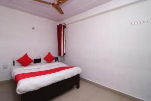 a small bedroom with a bed with red pillows at Four Seasons in Sikandra