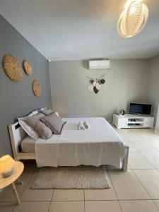 1 dormitorio con 1 cama blanca y TV en La Bohème, en La Paix