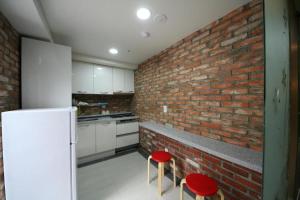 uma cozinha com uma parede de tijolos e dois bancos vermelhos em Star Guest House em Seul