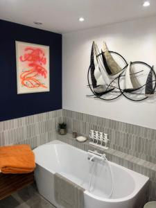 a bath tub in a bathroom with some art on the wall at Chambre dans Hôtel Particulier 18e siècle Hyper Centre La Rochelle in La Rochelle
