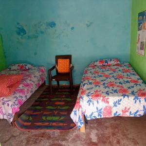 Un dormitorio con 2 camas y una silla. en Bhatt Homestay, en Uttarkāshi