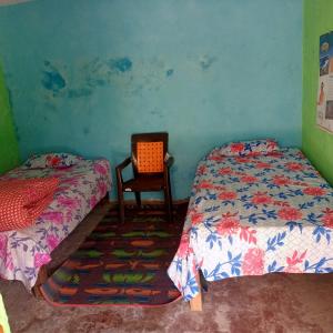 Un dormitorio con 2 camas y una silla. en Bhatt Homestay, en Uttarkāshi