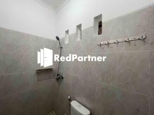 - une salle de bains avec un panneau rouge partenaire sur le mur dans l'établissement Hotel Pusponjolo Syariah Semarang Mitra RedDoorz, à Semarang