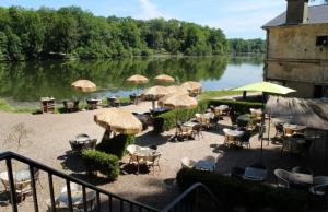 un grupo de mesas y sillas con sombrillas junto a un lago en Maison Individuelle Cozy Asterix, CDG, Paris, Disney, Olympic Games 2024 en La Chapelle-en-Serval