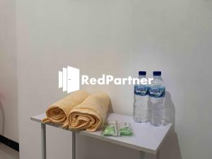 - une table avec un panneau rouge partenaire et 2 bouteilles d'eau dans l'établissement Hotel Pusponjolo Syariah Semarang Mitra RedDoorz, à Semarang
