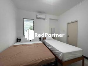 a small bedroom with a bed and a window at Hotel Pusponjolo Syariah Semarang Mitra RedDoorz in Semarang
