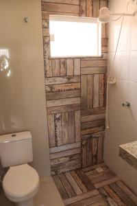 a bathroom with a toilet and a wooden wall at Casa de andar a 200m da areia Praia da Caueira SE in Praia Da Caueira +24 photos