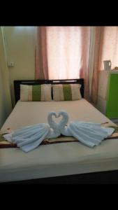 Dos cisnes hechos de toallas en una cama en Sonya Residence, en Patong Beach